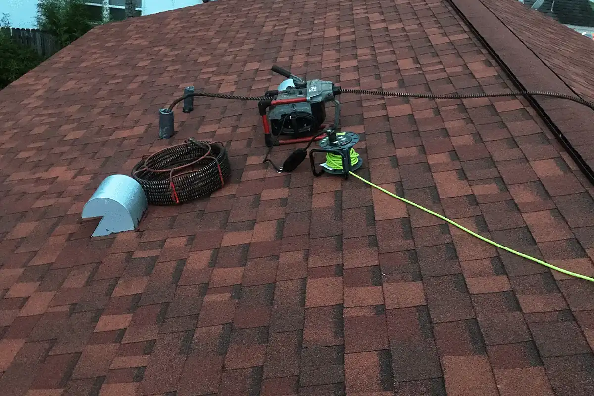 Drain cabling machine at a roof vent stack clearing a clogged line in Tampa